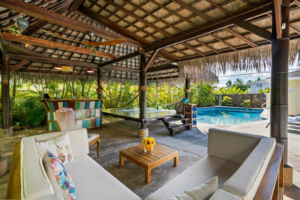 A serene pool area featuring a covered patio and a relaxing hammock, perfect for leisure and outdoor enjoyment.