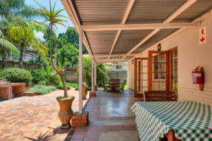 A patio featuring a table and chairs situated in front of a house, creating an inviting outdoor space for relaxation.